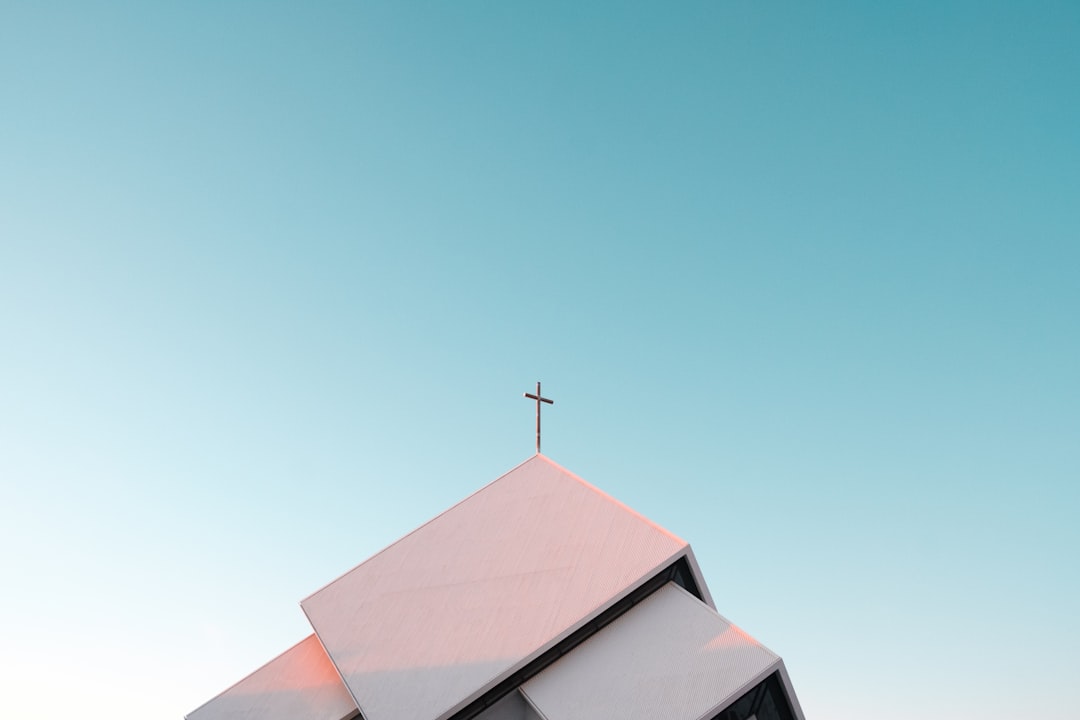 A white church roof with a cross against a clear blue sky