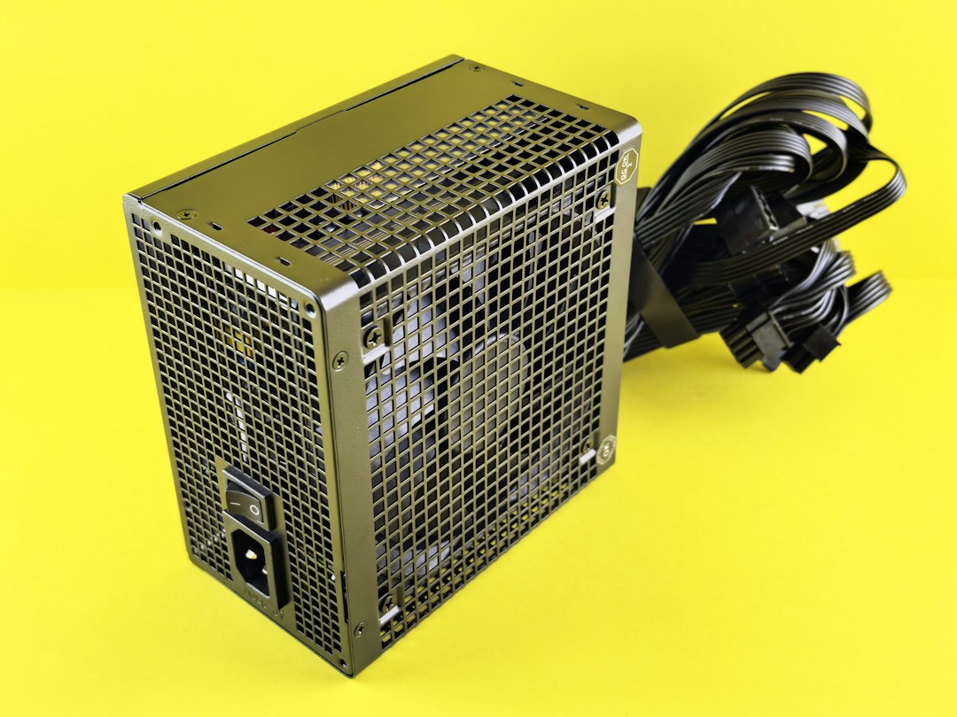 A black computer power supply unit with cables on a bright yellow background