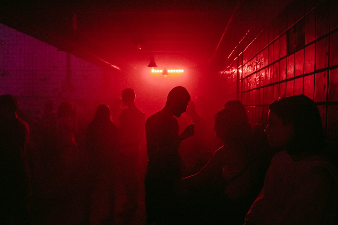 Silhouettes of people in a dark room illuminated by intense red light