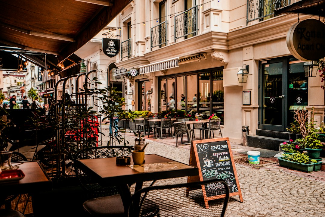 A cobblestone street with outdoor cafe tables and a chalkboard menu sign